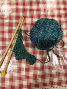 A ball of handspun being knitted into a shawl